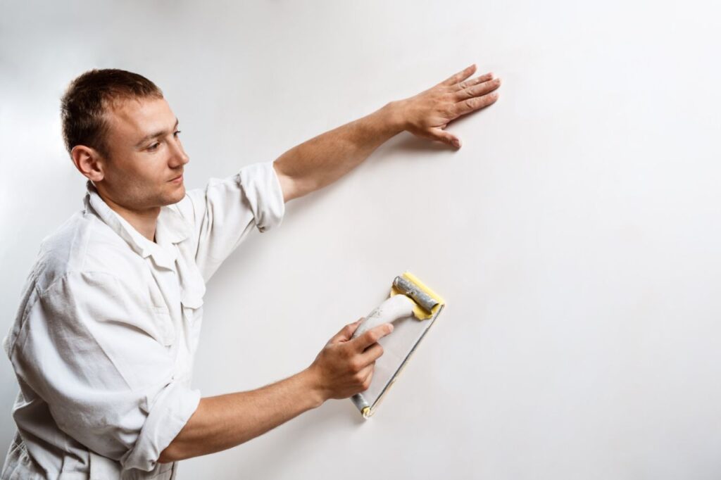 worker grinding white wall with sandpaper 1 1024x682