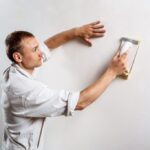 worker grinding white wall with sandpaper 1024x682